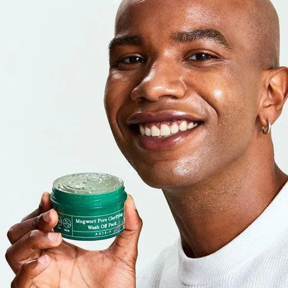 Smiling person holding Axis-Y Mugwort Pore Clarifying Wash Off Pack, Korean skincare product