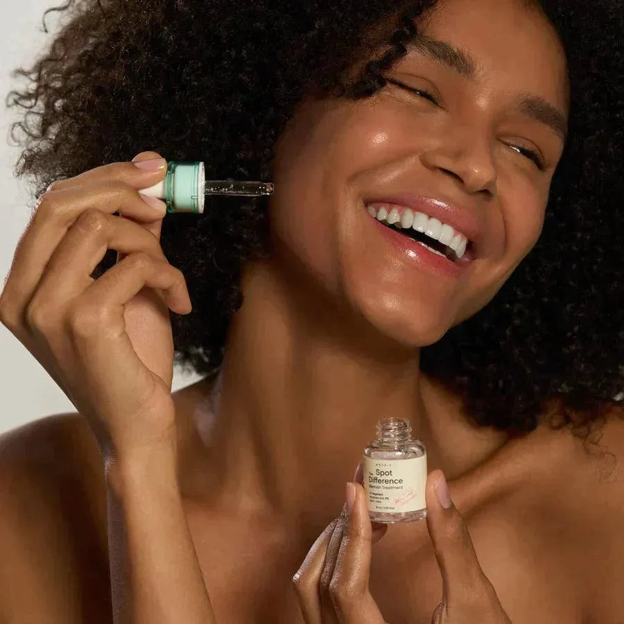 Smiling woman applying Axis-Y Spot The Difference Blemish Treatment, Korean skincare Nederland