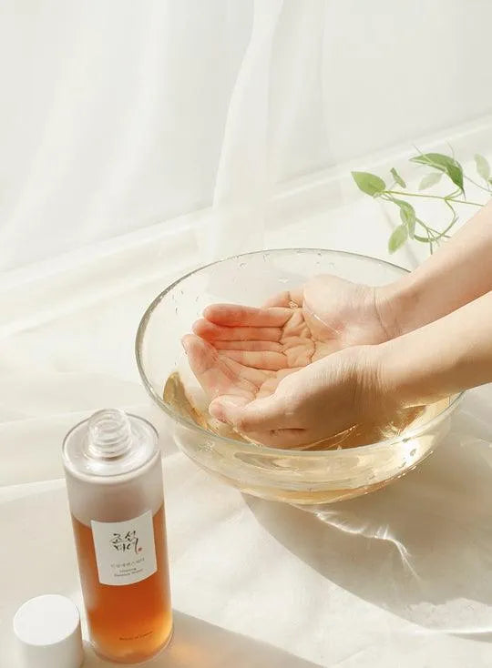 Hands cupping water in a glass bowl beside Beauty of Joseon Ginseng Essence, Korean skincare