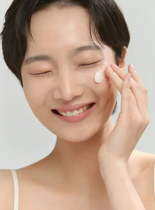 Smiling woman applying Korean skincare cleansing balm to face, Me Time Groningen
