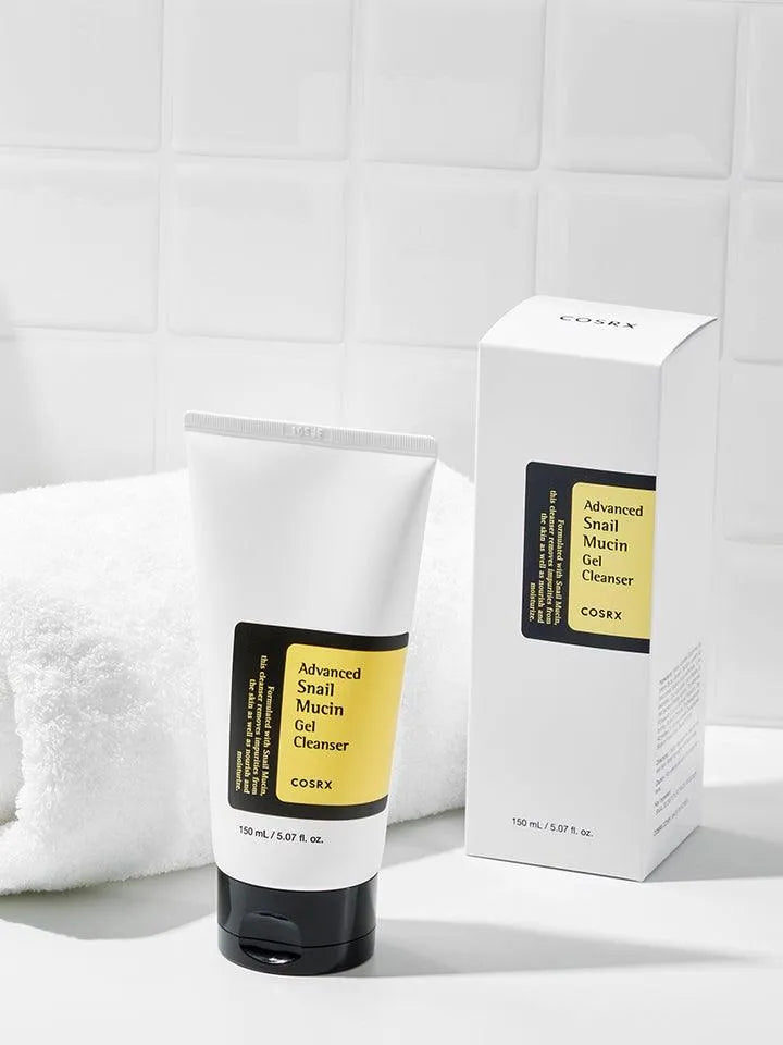 COSRX Advanced Snail Mucin Gel Cleanser tube and box on white towel in a tiled bathroom setting