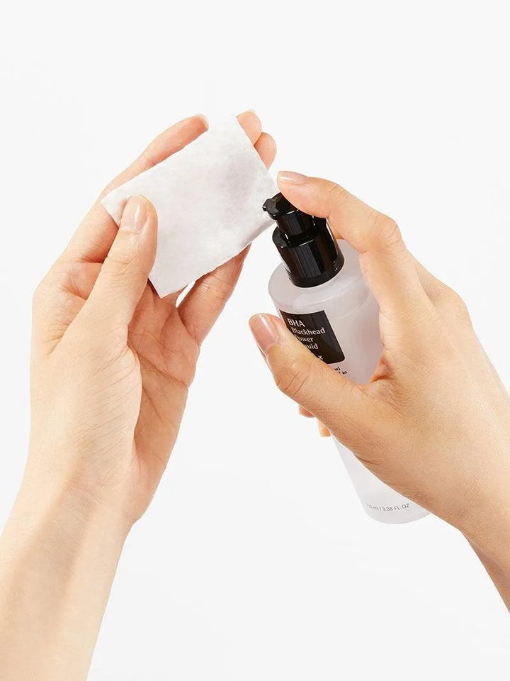 Hand applying COSRX BHA Blackhead Power Liquid to cotton pad, Korean skincare Nederland