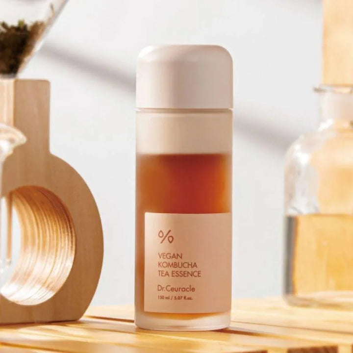 Dr. Ceuracle Vegan Kombucha Tea Essence bottle on wooden surface, Korean skincare product