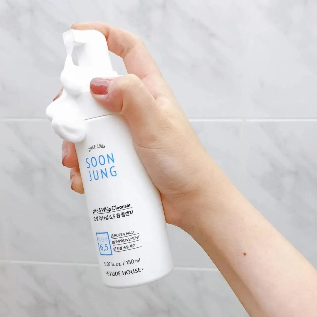 Hand holding Etude House Soon Jung pH 6.5 Whip Cleanser bottle with foam, Korean skincare product