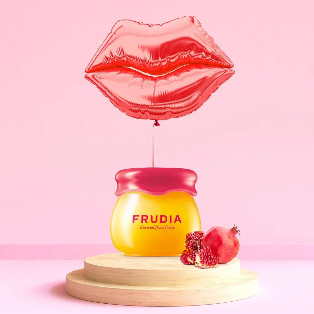 Frudia Pomegranate Honey 3-in-1 Lip Balm with pomegranate and lip balloon on pink background