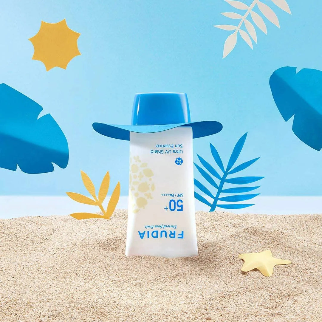 Frudia Ultra UV Shield Sun Essence SPF 50 tube with blue cap as hat on sand, beach scene, Korean skincare