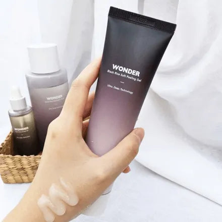 Hand holding Haruharu Wonder Black Rice Soft Peeling Gel with skincare set, Korean skincare