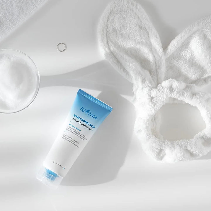 Isntree hyaluronic acid low pH cleansing foam, fluffy bunny headband, and foam on white surface