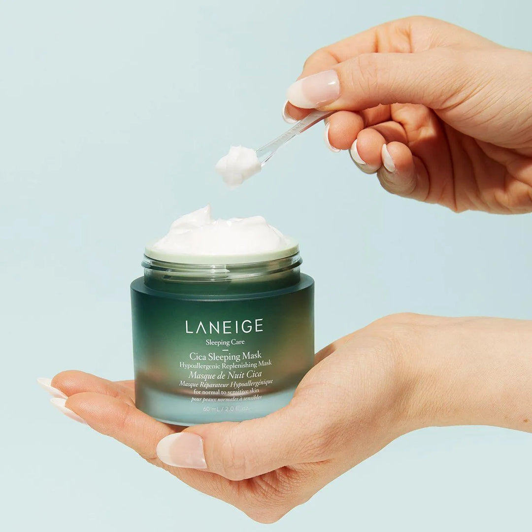 Hand holding Laneige Cica Sleeping Mask jar, applying Korean skincare cream with spatula.