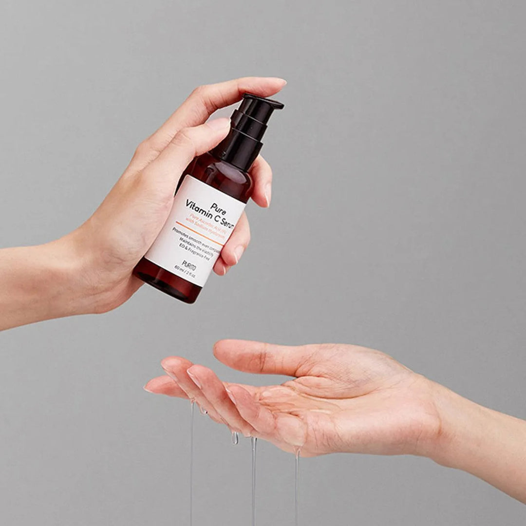 Hand dispensing Purito Pure Vitamin C Serum, Korean skincare product, on light background