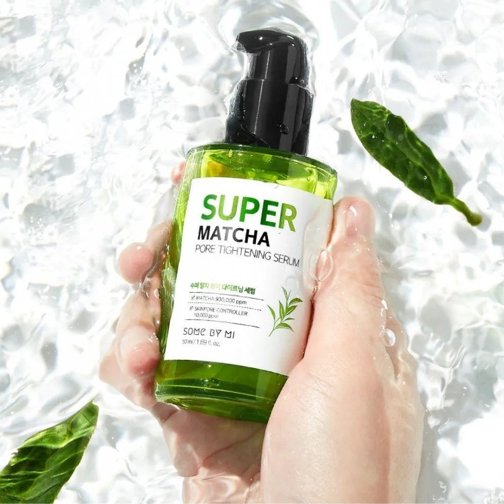 Hand holding Some By Mi Super Matcha Pore Tightening Serum bottle with water and leaves