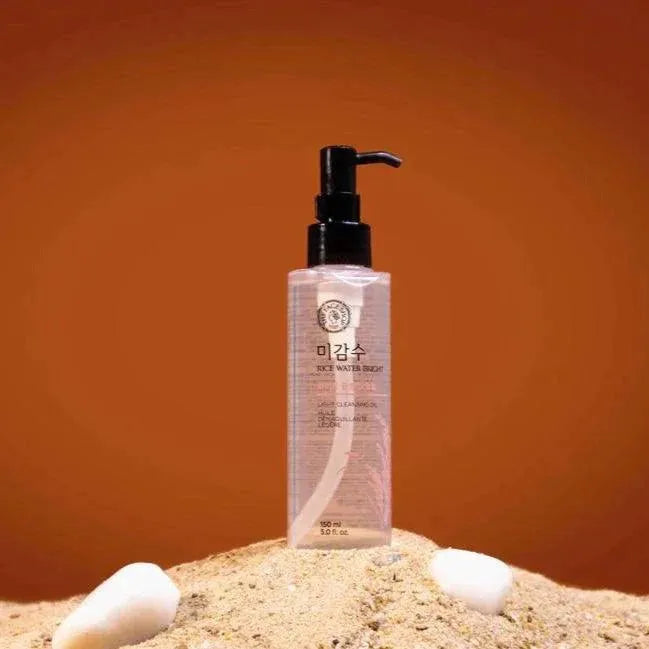 The Face Shop Rice Water Bright Rich Cleansing Oil bottle on sand with an orange background, Korean skincare product at Me Time Groningen.